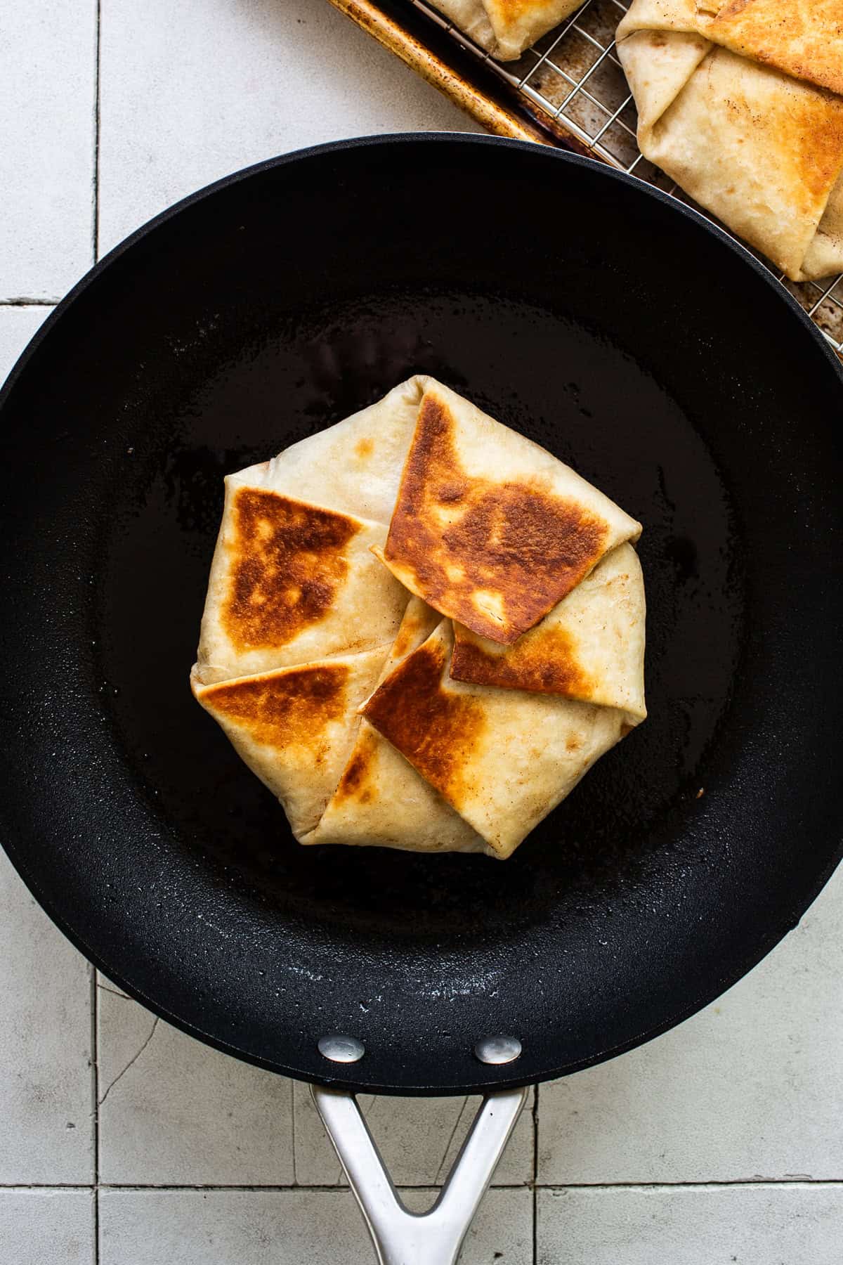 A toasted crunchwrap supreme in a skillet.
