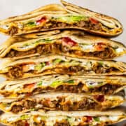Cross sections of many crunchwrap supremes stacked on top of one another.