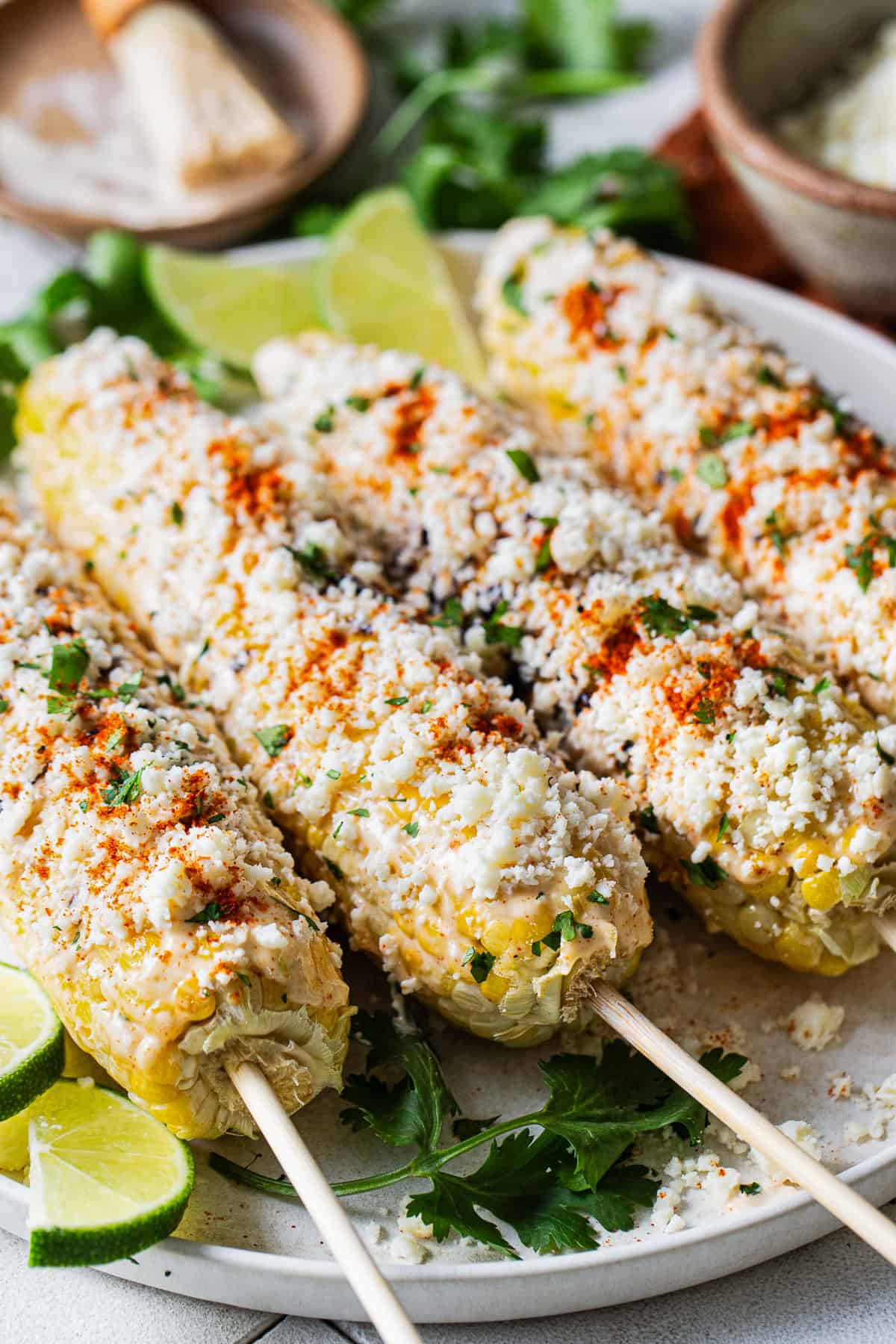 Elote (Mexican street corn) on sticks with all the toppings ready to serve.