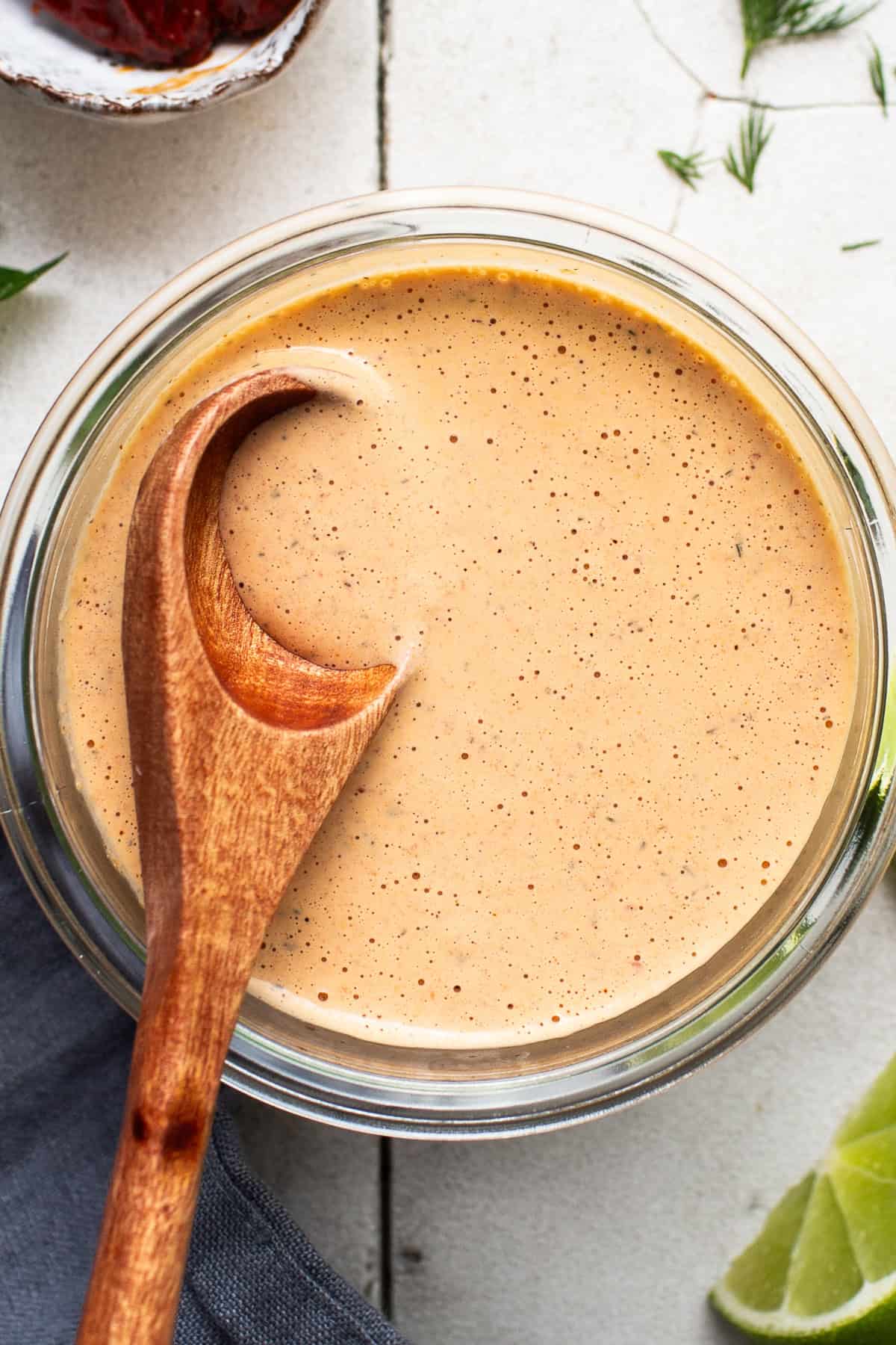 A close up image of chipotle ranch in a jar with a wooden spoon in it to show the creamy texture.