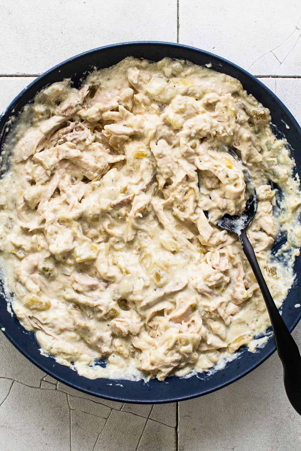The shredded chicken and cream cheese filling stirred together in a skillet.