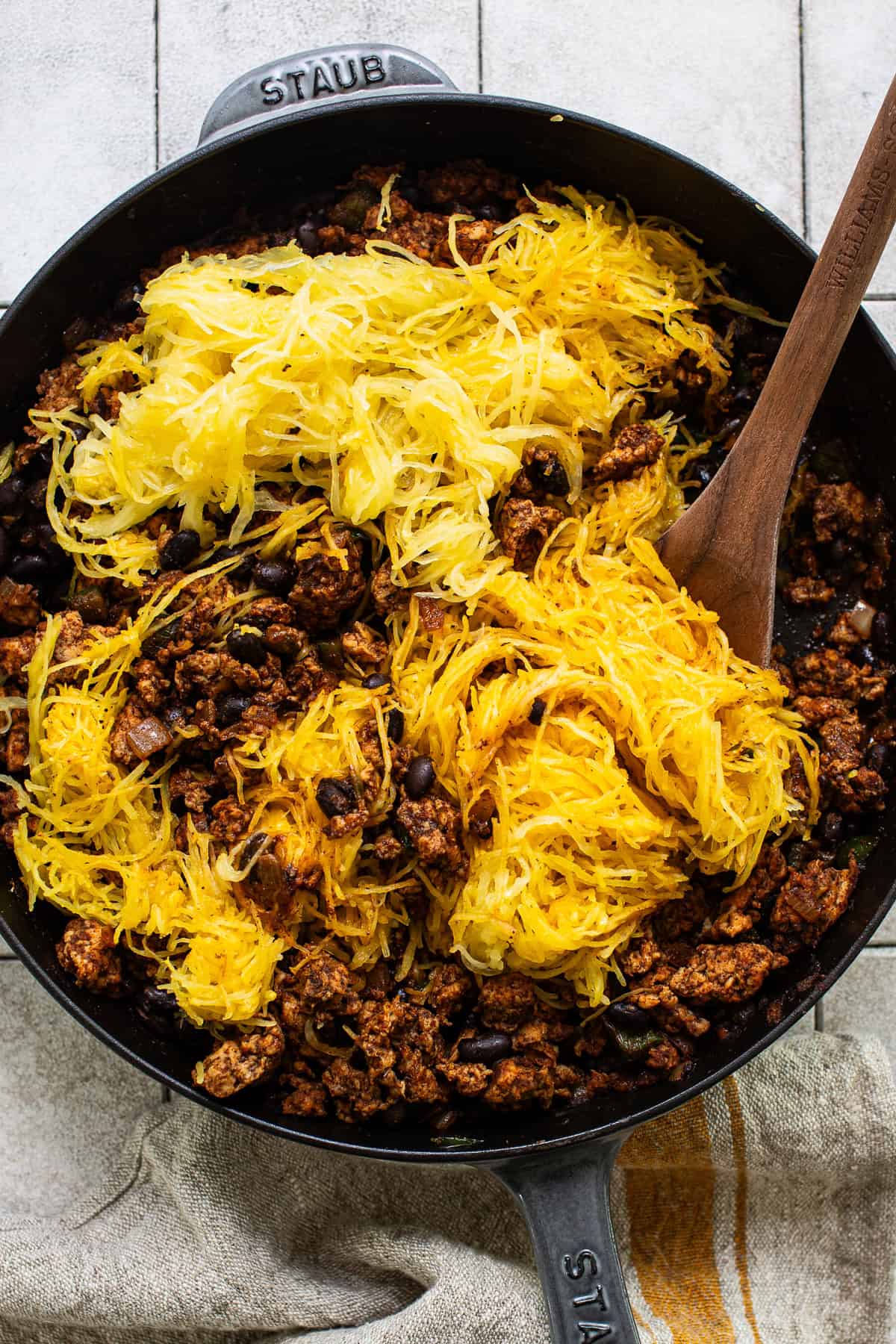 Spaghetti squash noodles being mixed into the ground chicken and black bean filling.