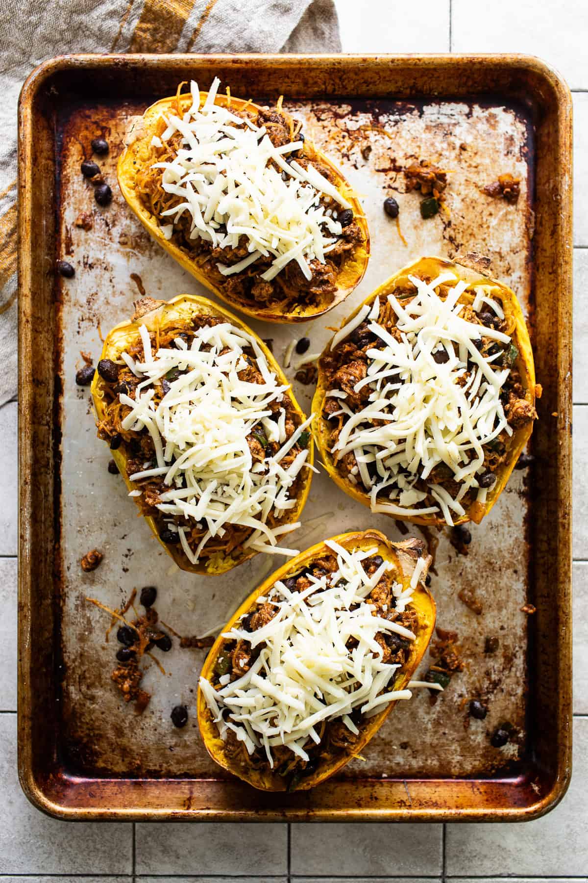 Shredded cheese topped on spaghetti squash boats.