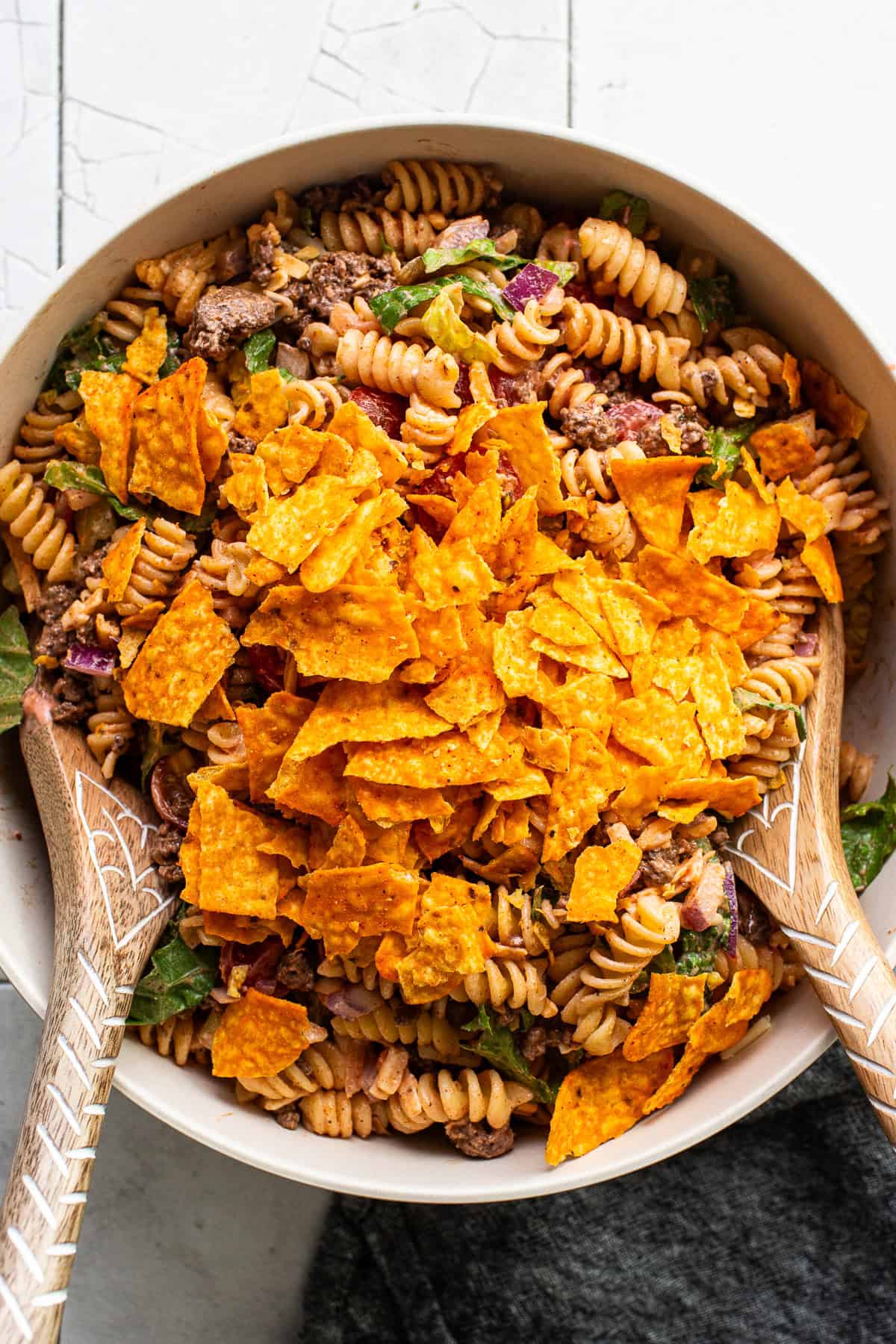 Crushed Doritos on top of taco pasta salad before being mixed together.
