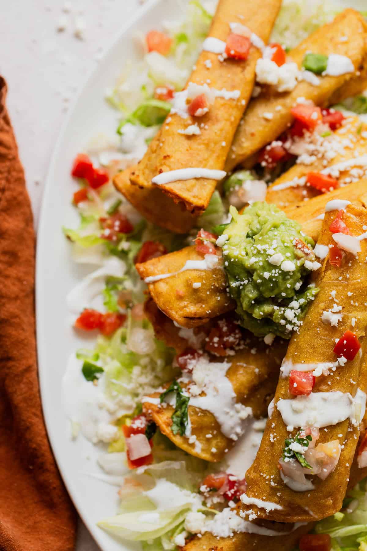 Taquitos drizzled with Mexican crema and served with a dollop of guacamole.