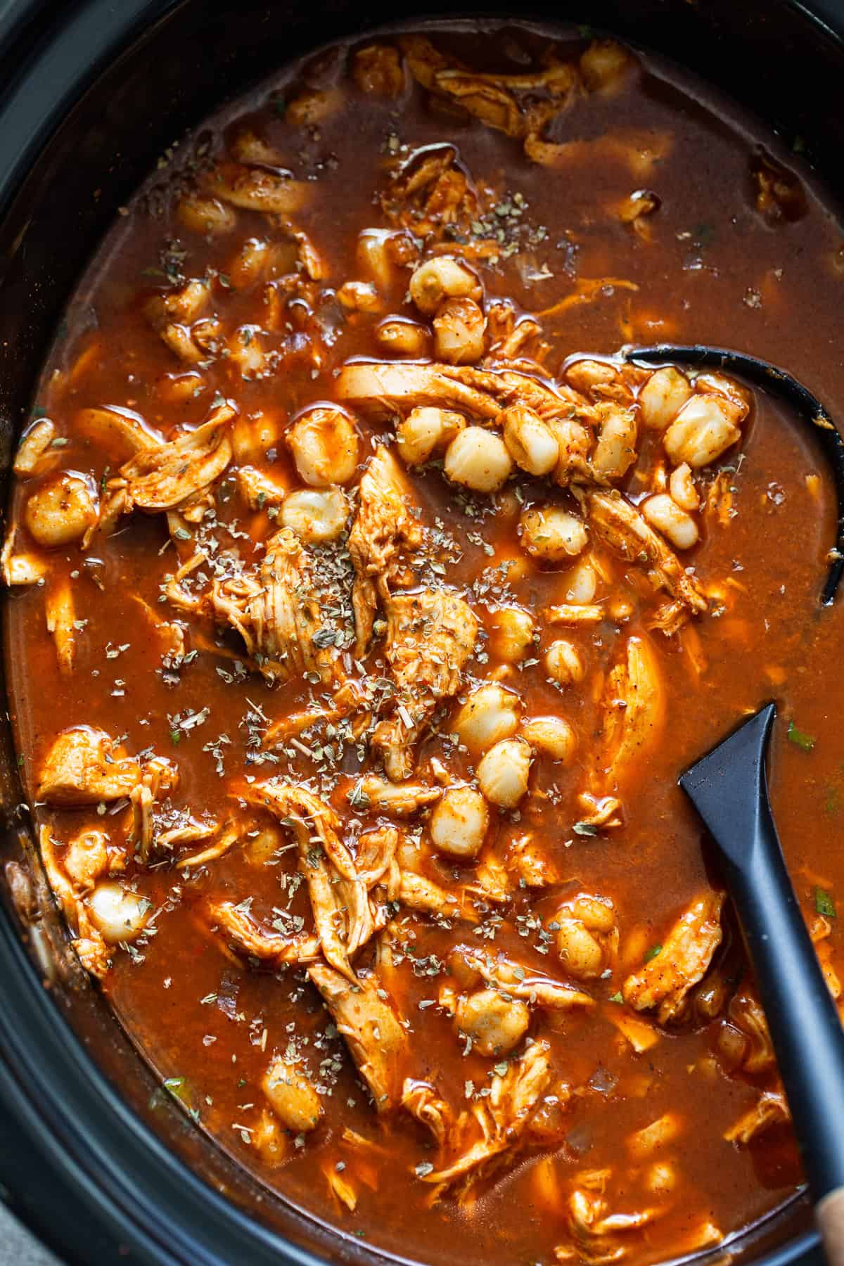 Chicken pozole in the slow cooker pot topped with dried Mexican oregano.