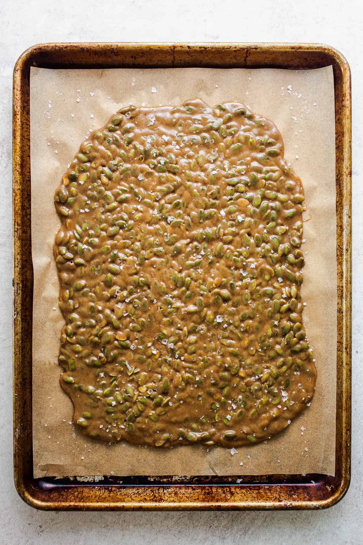The warm brittle candy spread out on a baking sheet to cool.