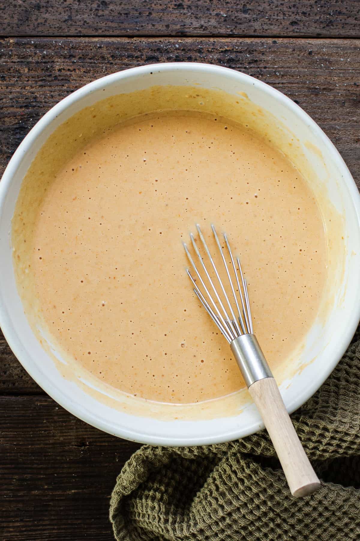 Batter for pumpkin buñuelos de viento in a bowl with a whisk.