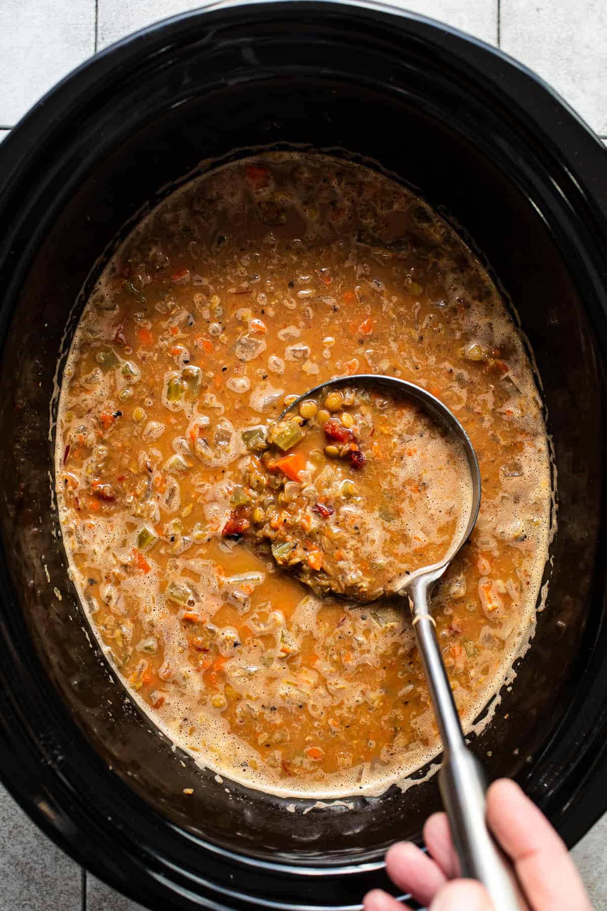 The finished soup in the slow cooker with a ladle.