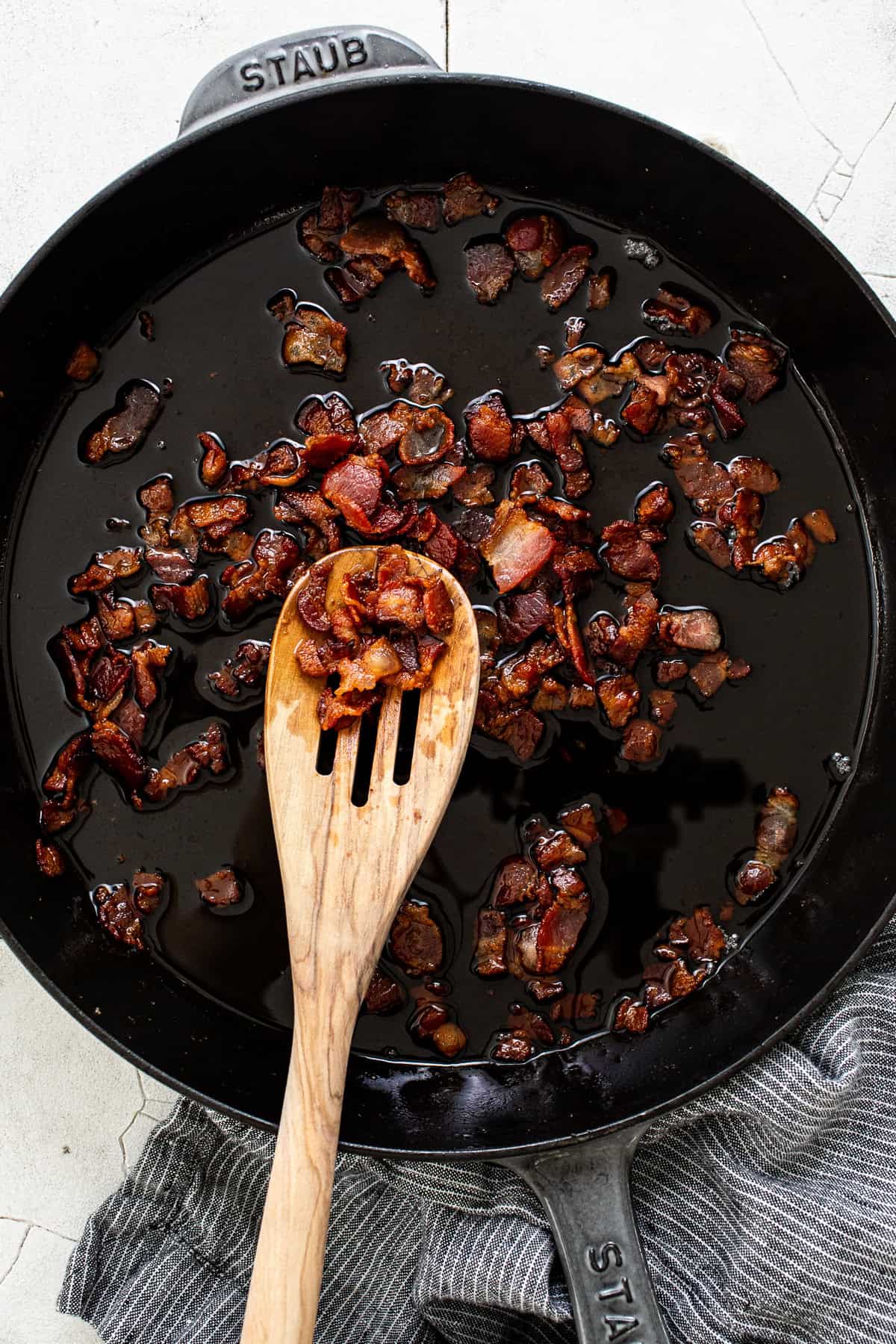 Crispy, cooked diced bacon in a skillet.