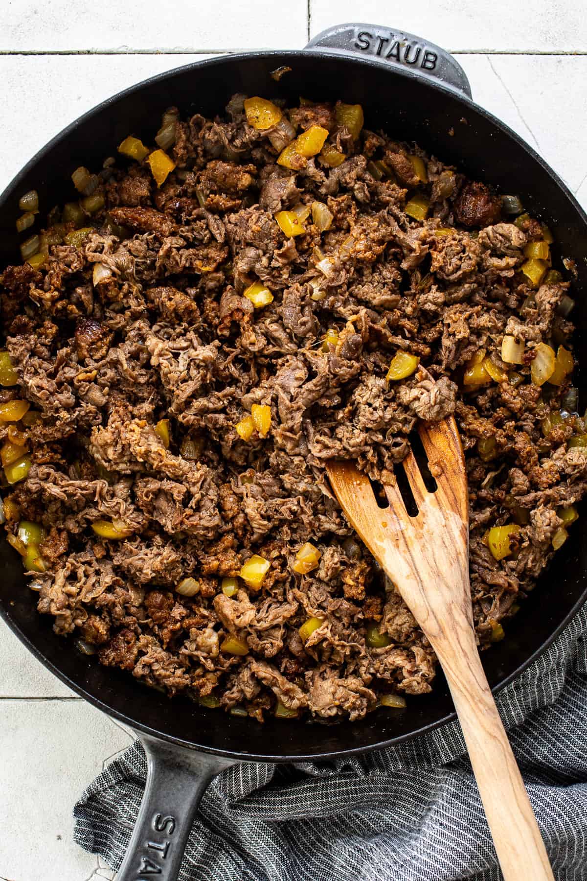 Shaved steak, chorizo, peppers, and onions cooked in a skillet for tacos de alambre.
