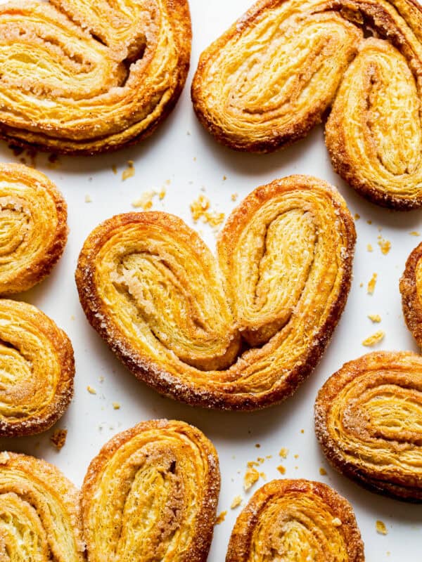 Crispy orejas pan dulce on a baking sheet with lots of cinnamon sugar.