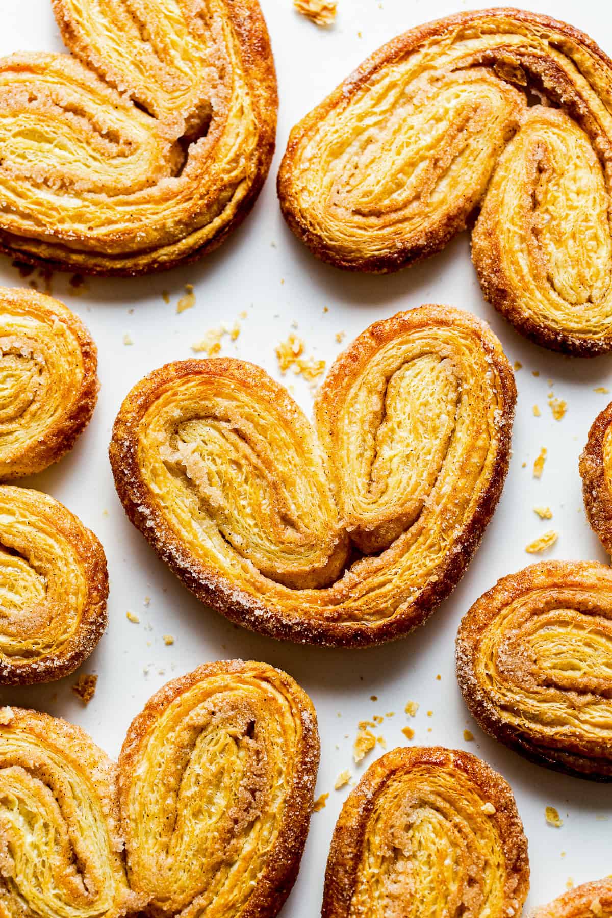 Crispy orejas pan dulce on a baking sheet with lots of cinnamon sugar.