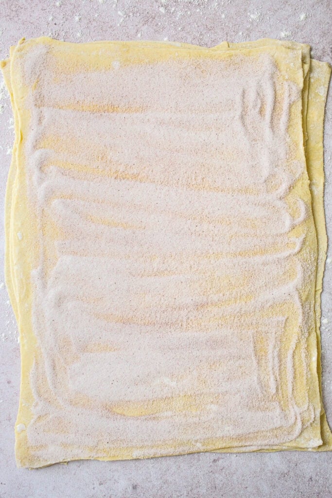 Four sheets of rolled out puff pastry dough sprinkled with cinnamon sugar.