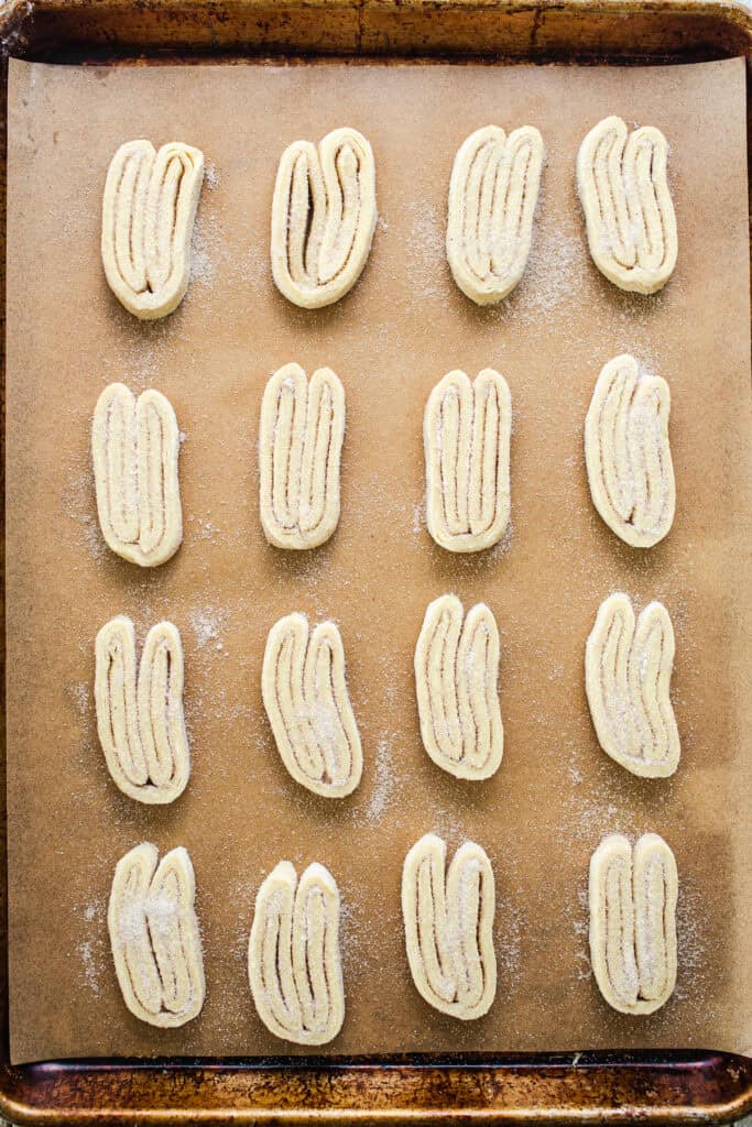 Uncooked slices of orejas on a baking sheet lined with parchment paper.
