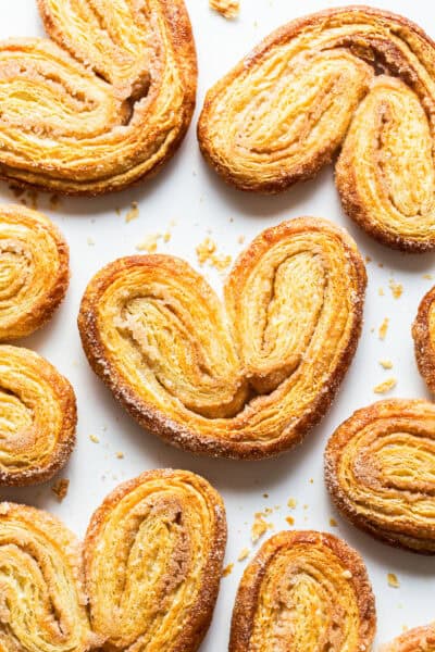 Crispy orejas pan dulce on a baking sheet with lots of cinnamon sugar.