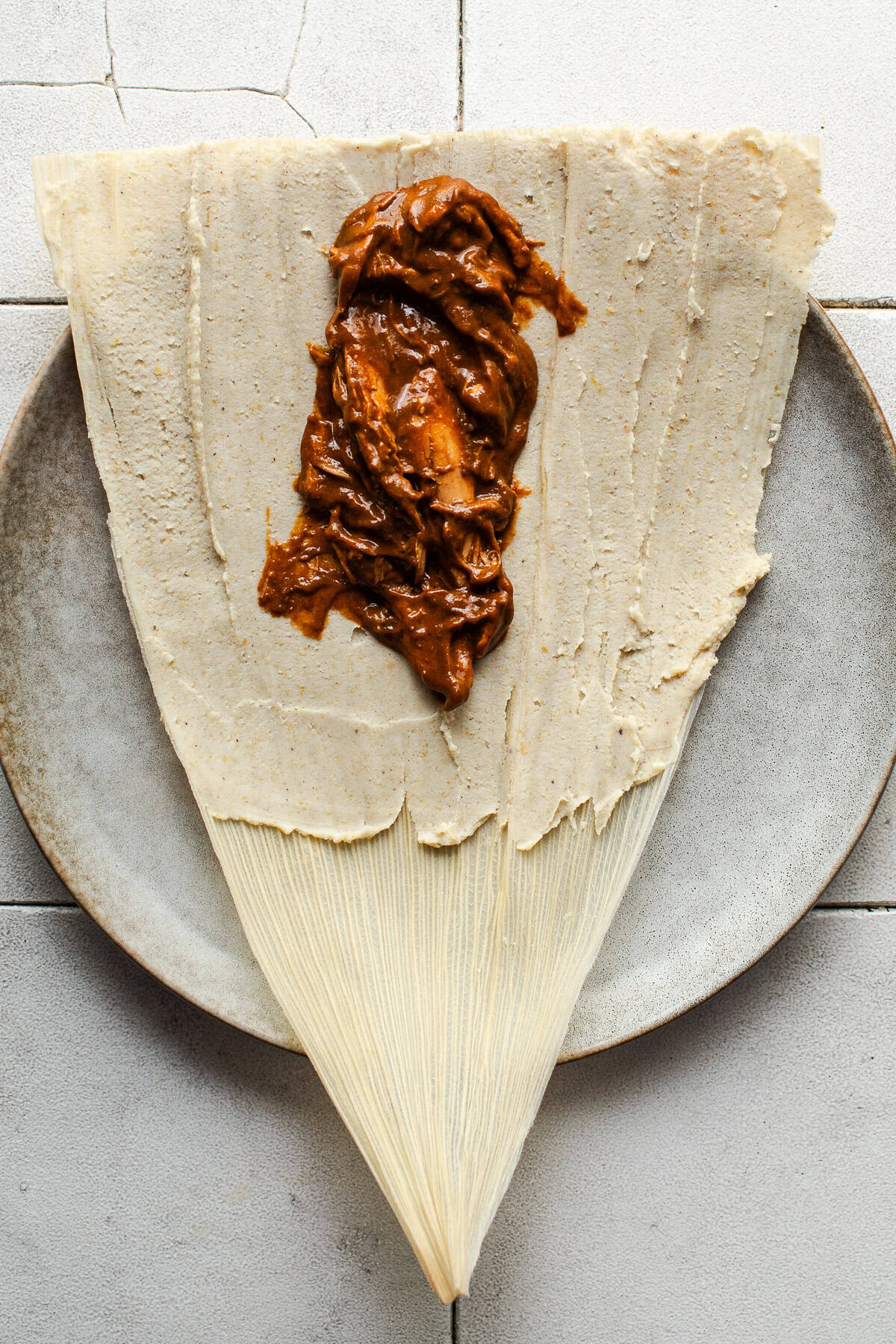 A chicken mole tamal being assembled on a plate
