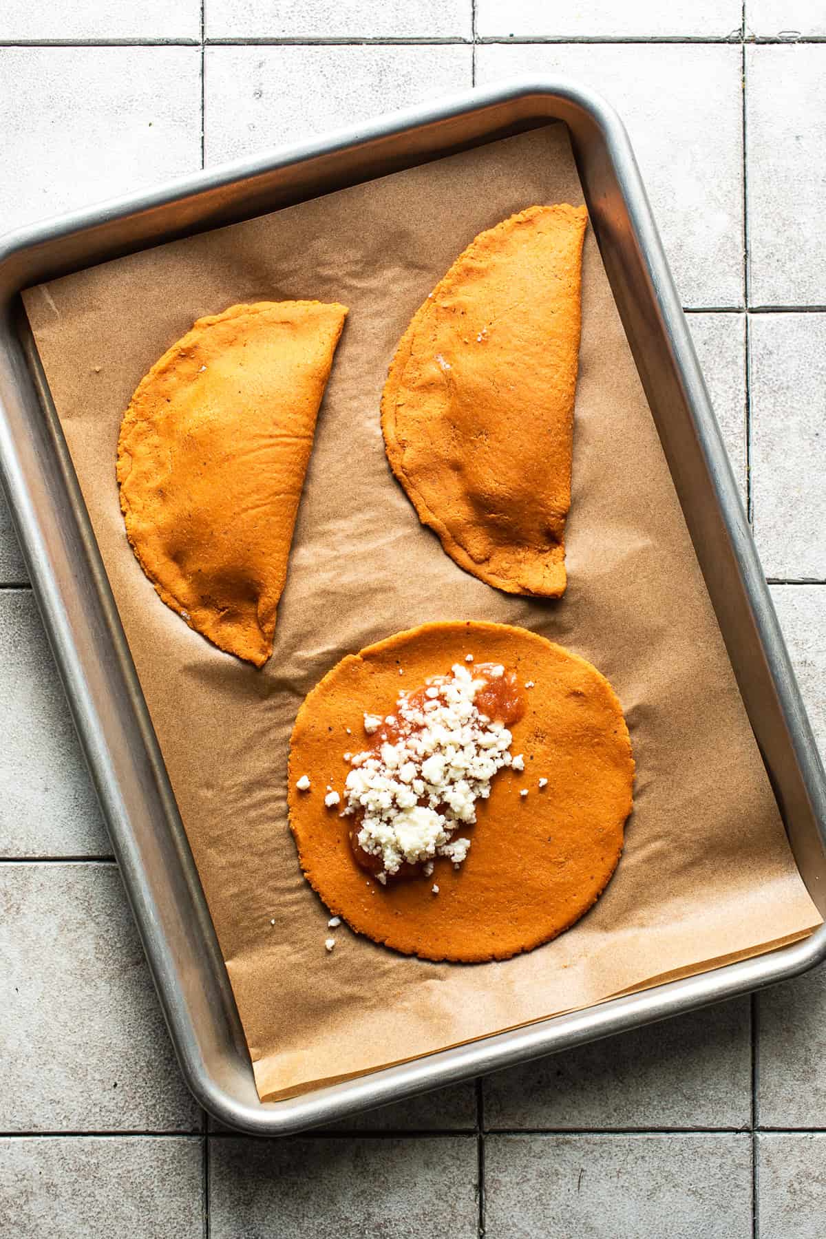 The chile-infused masa dough for enchiladas potosinas with some fresh salsa and queso fresco on top before being folded over and fried.