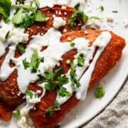 Enchiladas potosinas on a plate drizzled with crema, cotija cheese, and cilantro.