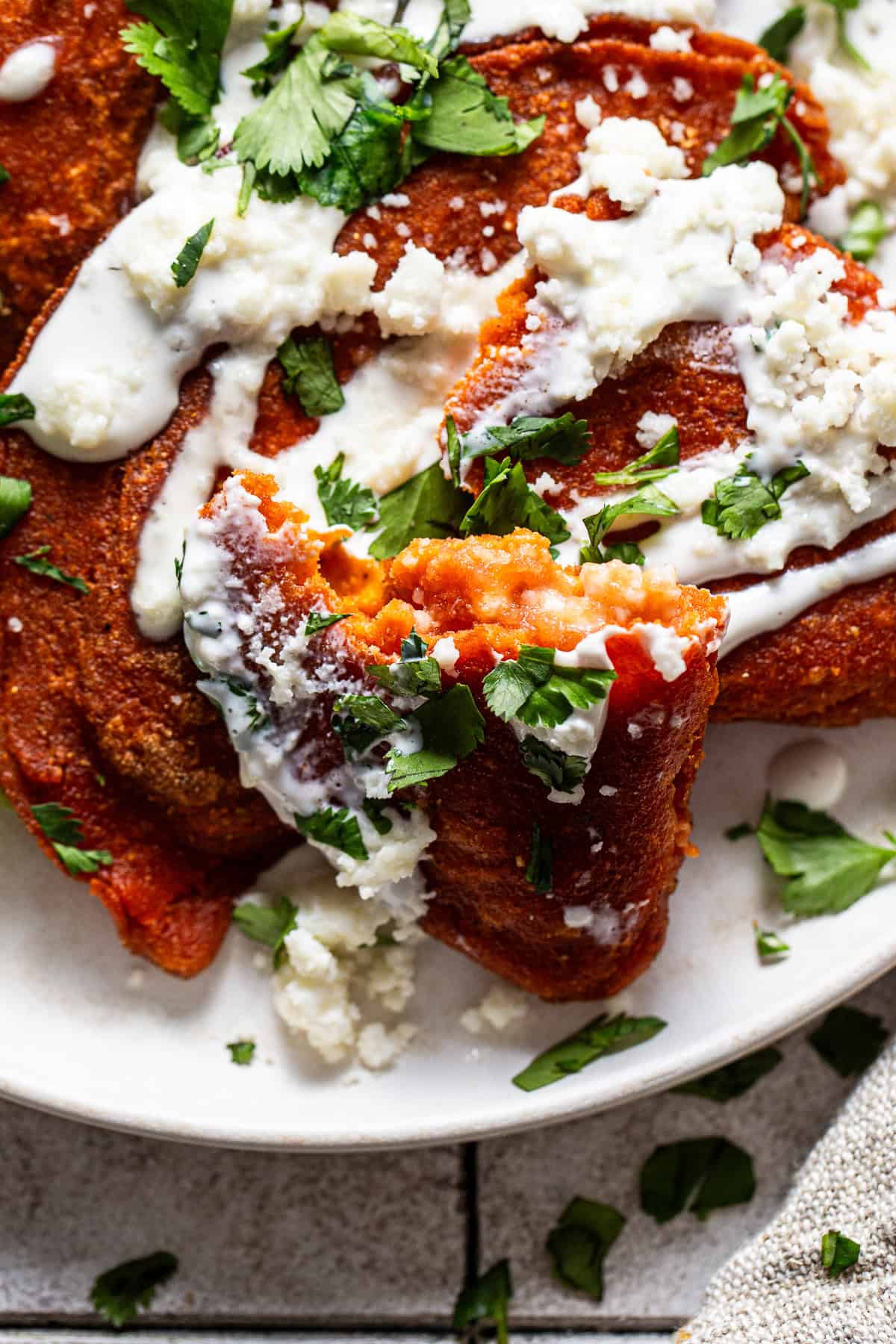 An enchilada potosina torn in half so you can see the filling of cheese and salsa.