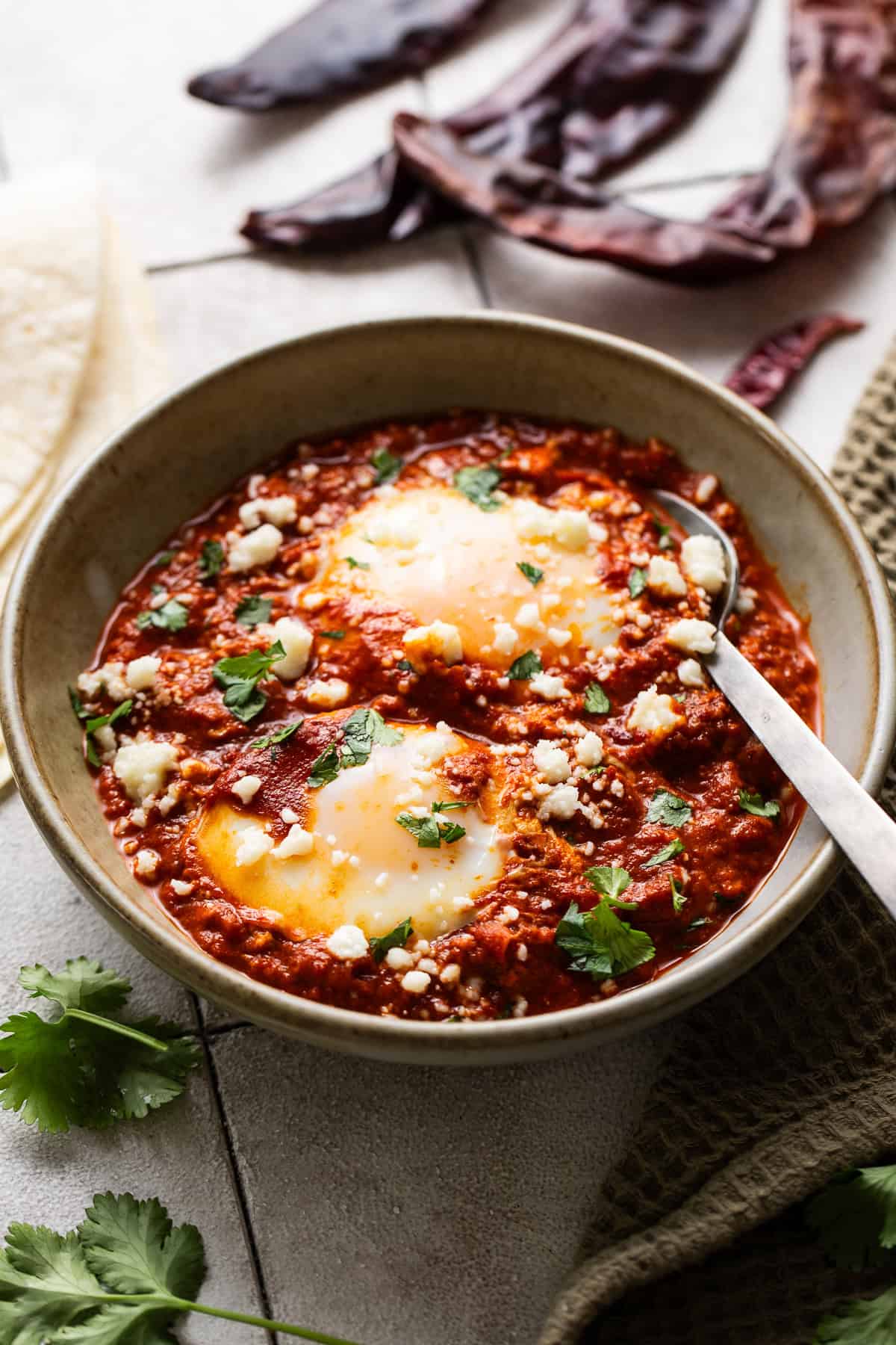 A bowl of huevos ahogados garnished with cilantro and cotija cheese.