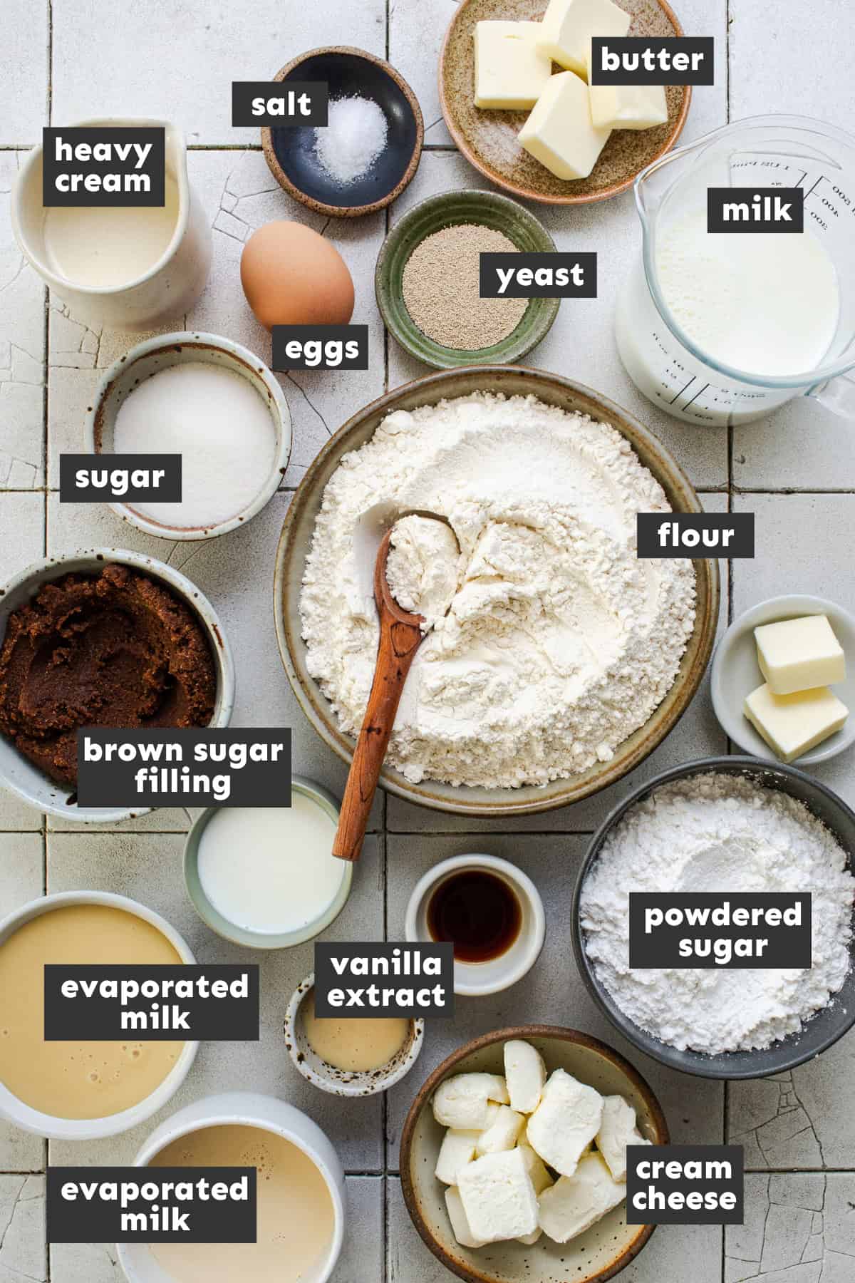 Ingredients for tres leches cinnamon rolls on a table in small bowls and ramekins