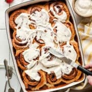 Tres leches cinnamon rolls with cream cheese icing in a tray ready to serve.