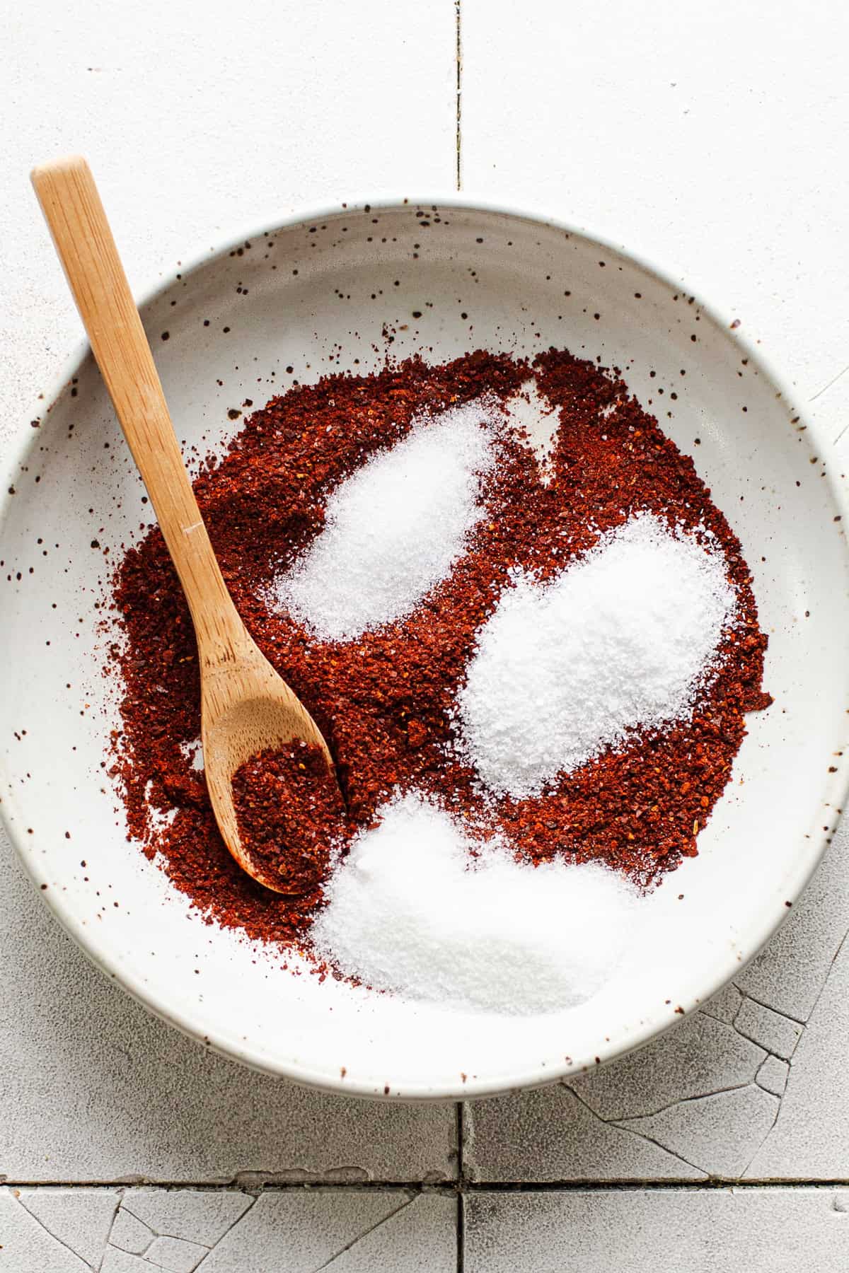 Ground guajillo chiles, salt, citric acid, and sugar in a small bowl before being mixed together.