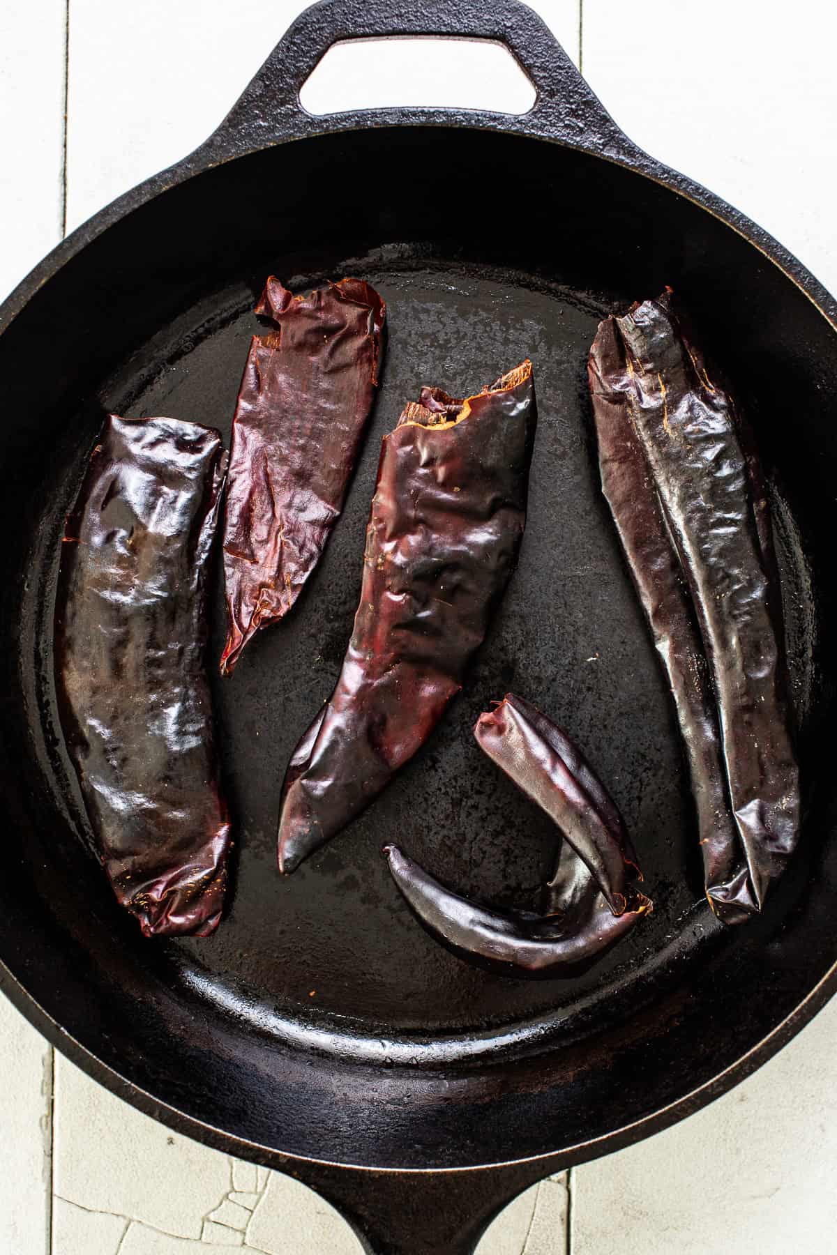Guajillo chiles toasting in a dry cast iron skillet.