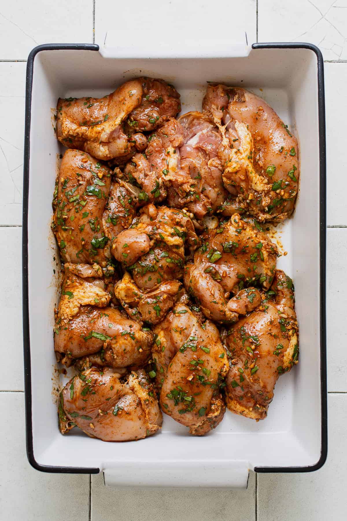 The coated and marinated chicken in a baking dish before being cooked or grilled.