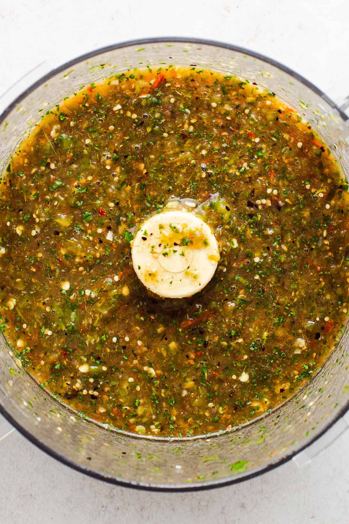 A roasted tomatillo salsa verde in a food processor ready to be served with rotisserie chicken tacos.