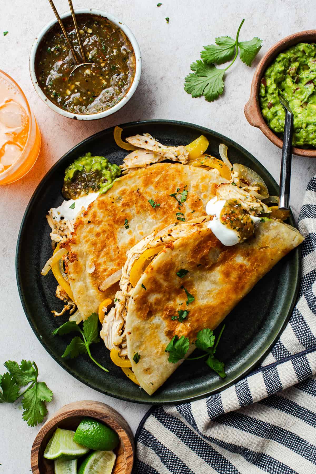 A plate with two rotisserie chicken tacos on it with salsa and sour cream.