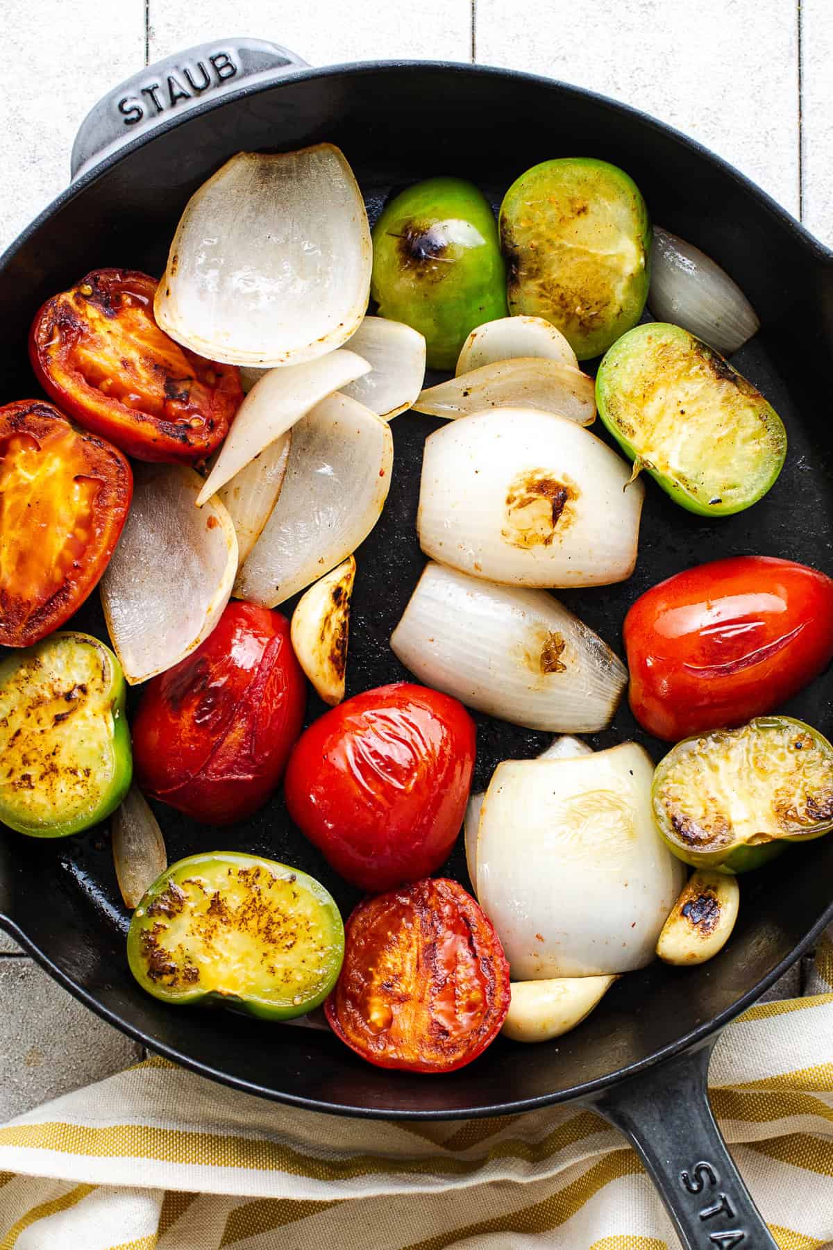 Tomatoes, onions, tomatillos, garlic, and árbol chiles in a skillet for salsa roja.