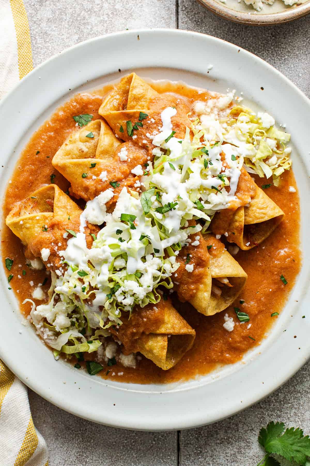Flautas ahogadas drowned in salsa roja on a plate.
