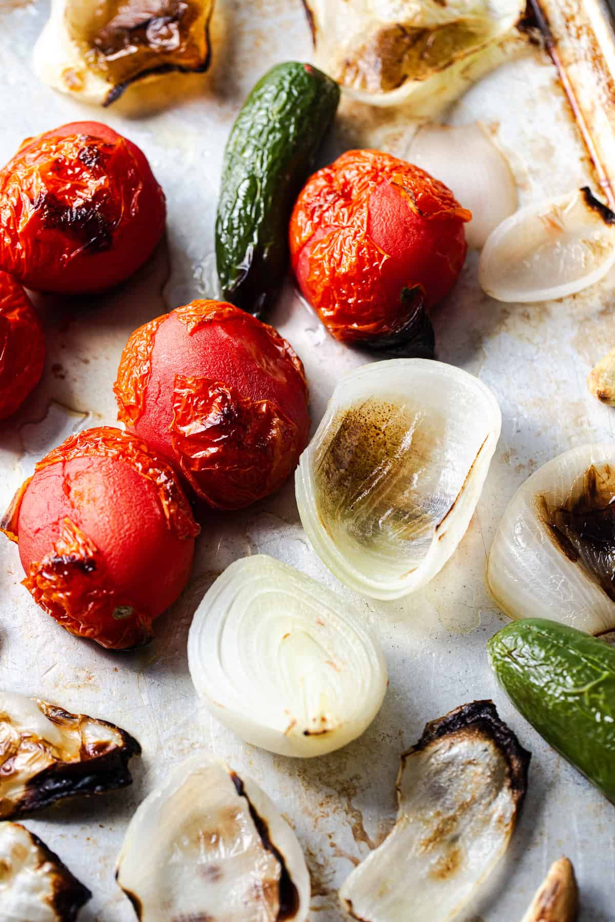 Roasted tomatoes, peppers, and onions on a baking sheet.