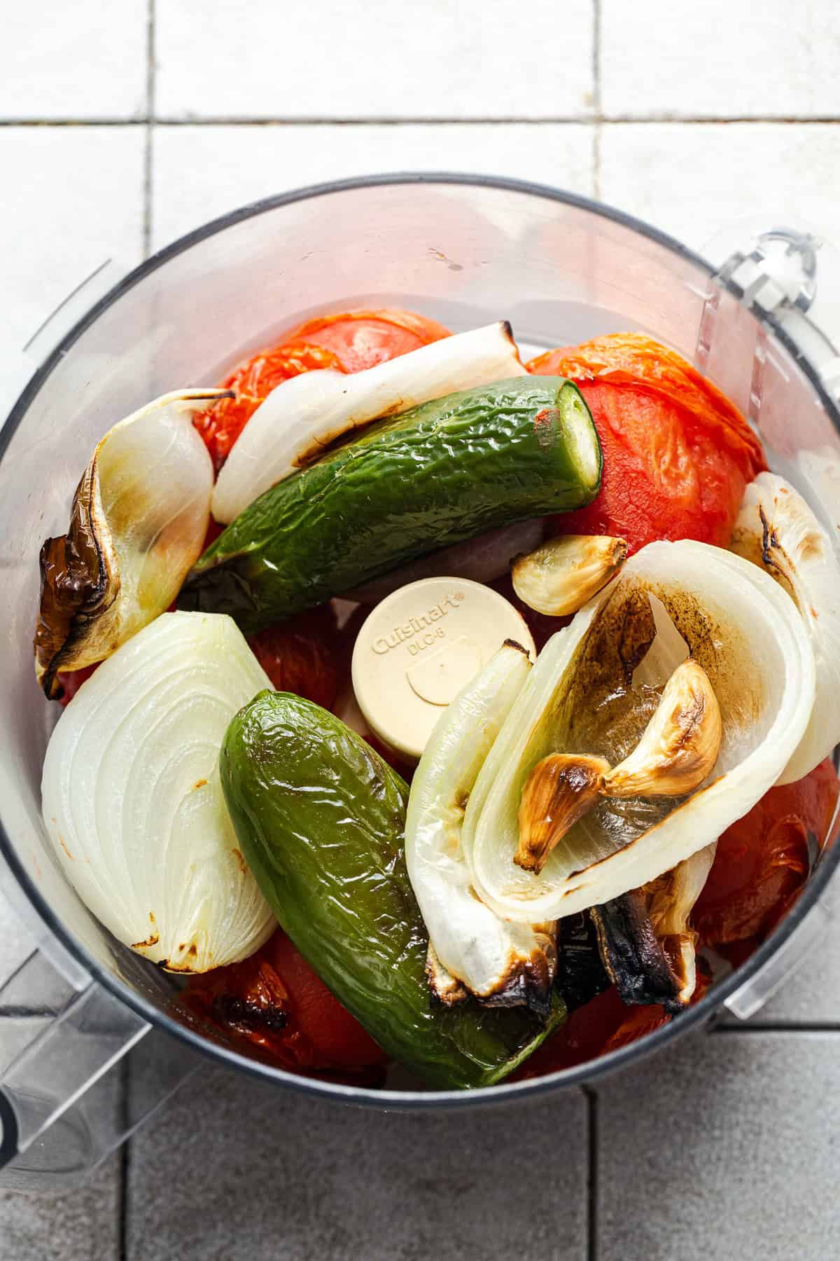 Roasted tomatoes, onions, jalapeños, and garlic in a food processor before being blended.