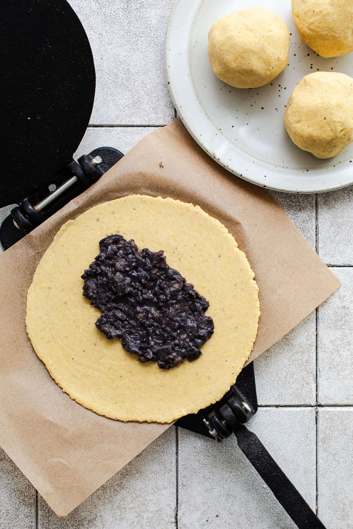 Pressed masa harina with black beans in the middle before being shaped into tlacoyos.