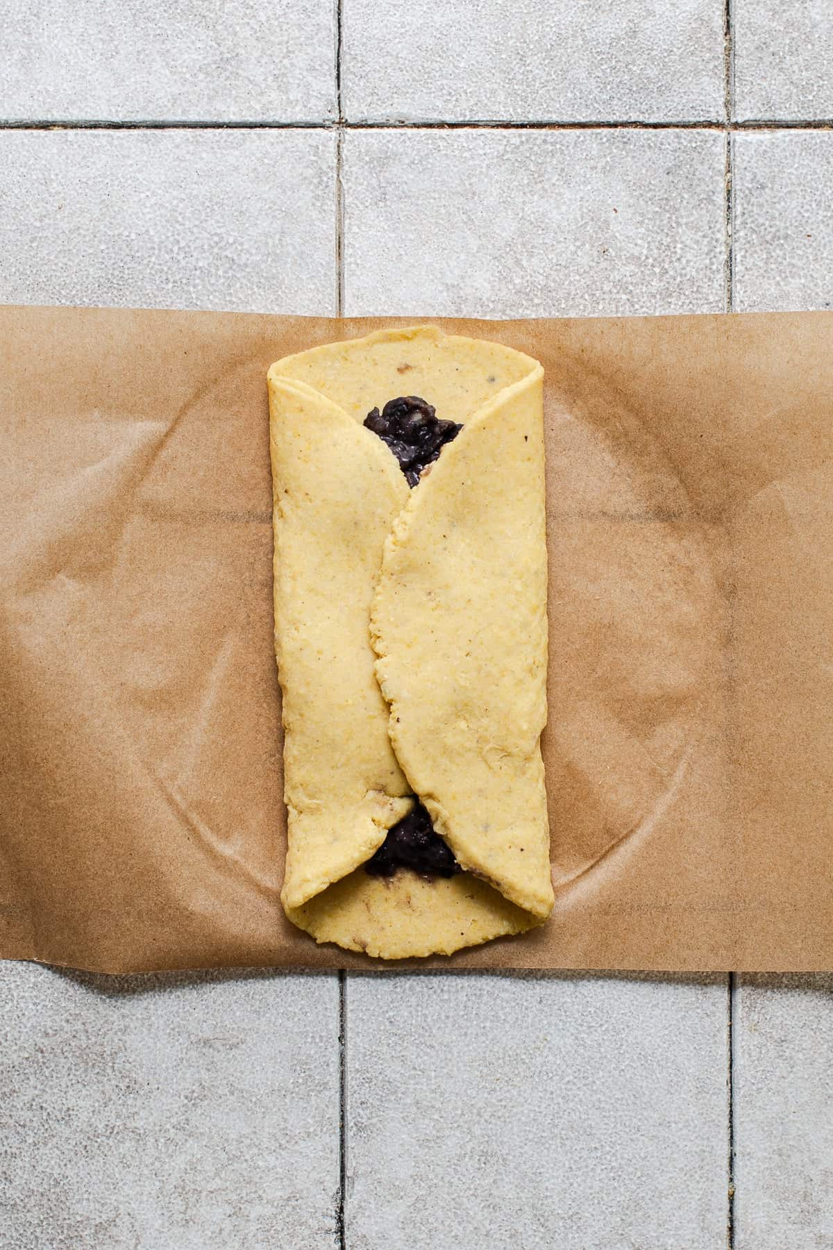 The two sides of pressed masa dough closed over mashed black beans to form tlacoyos.