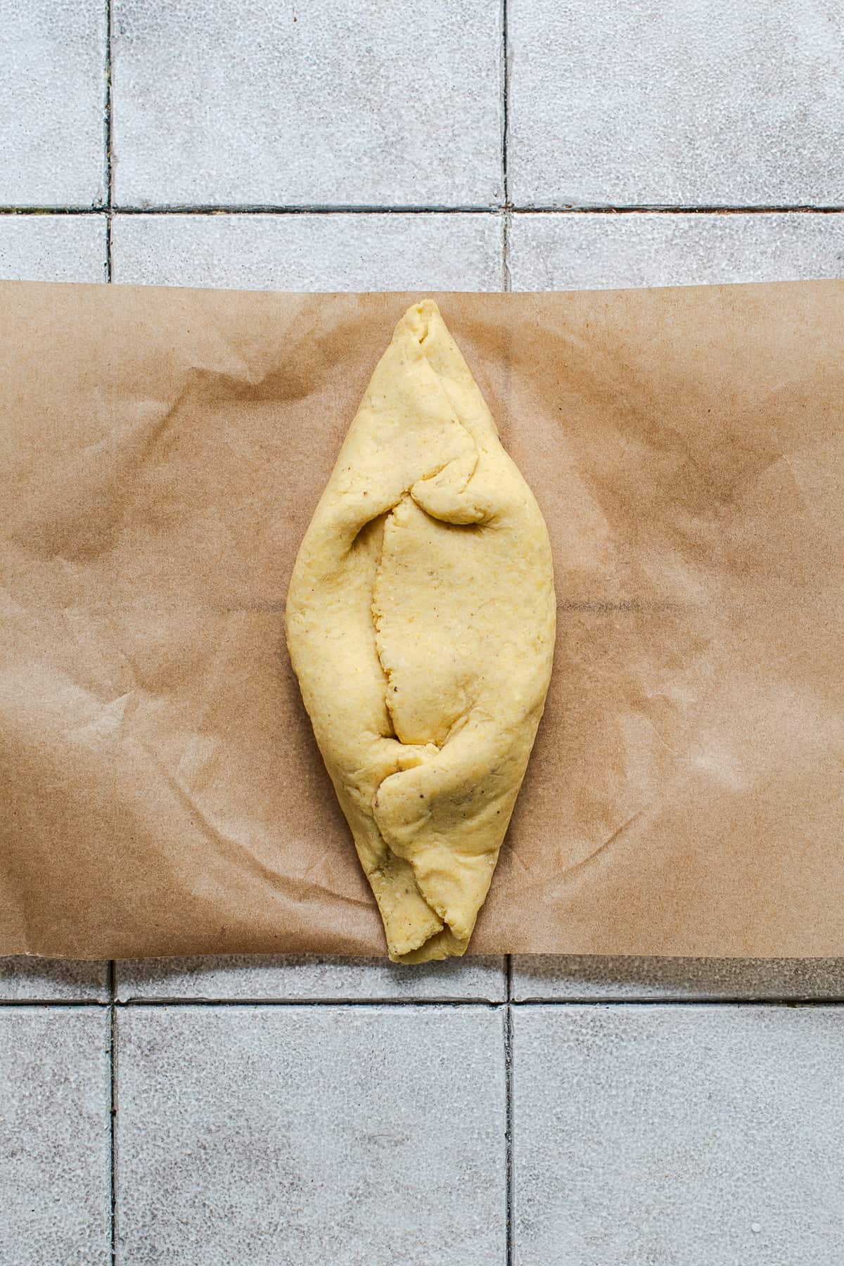 The top edges of the pressed masa dough folded into the center to create a football shape for tlacoyos.