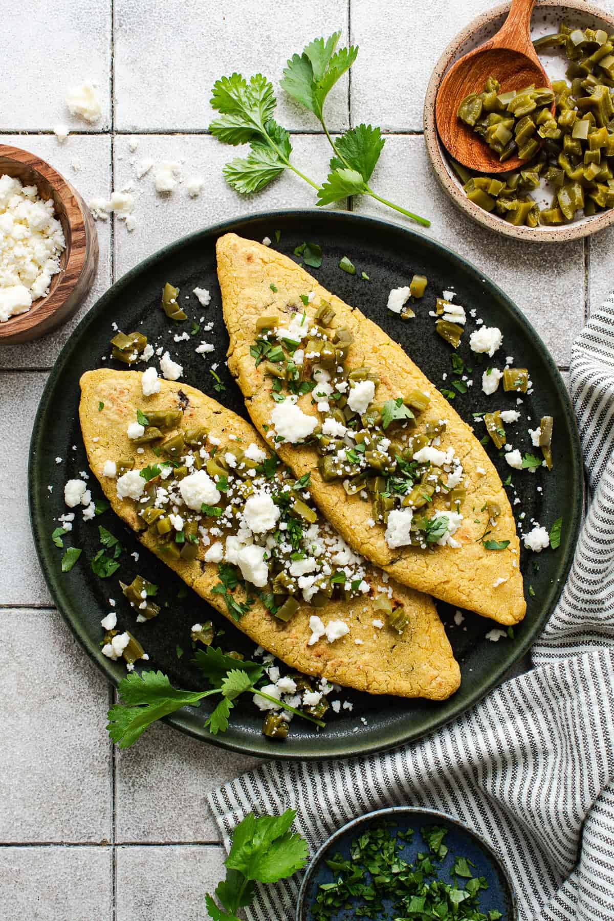 Tlacoyos on a plate with diced nopales on top and garnished with cilantro and queso fresco.