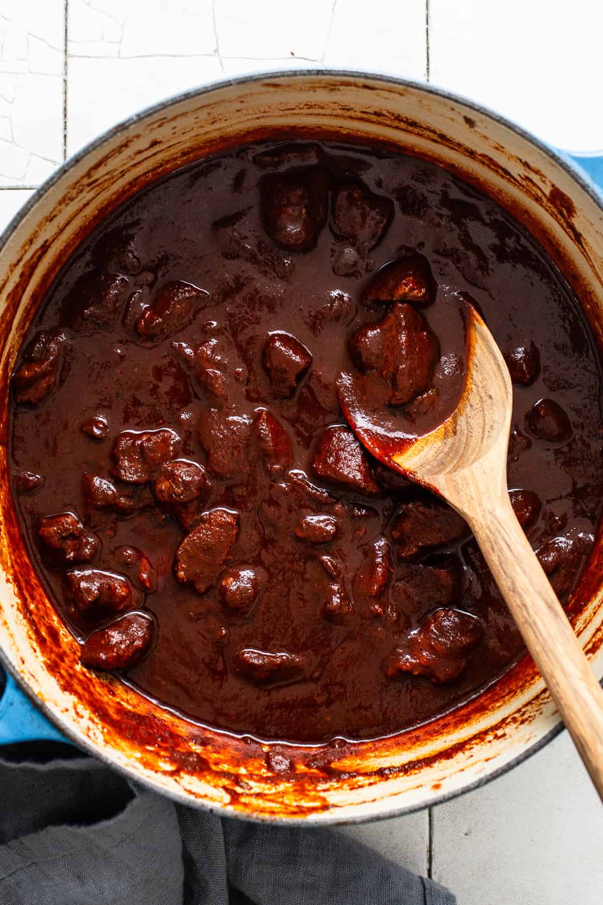 Carne adovada in a large pot ready to be served with a wooden spoon.