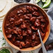 Carne adovada in a bowl next to warm tortillas.