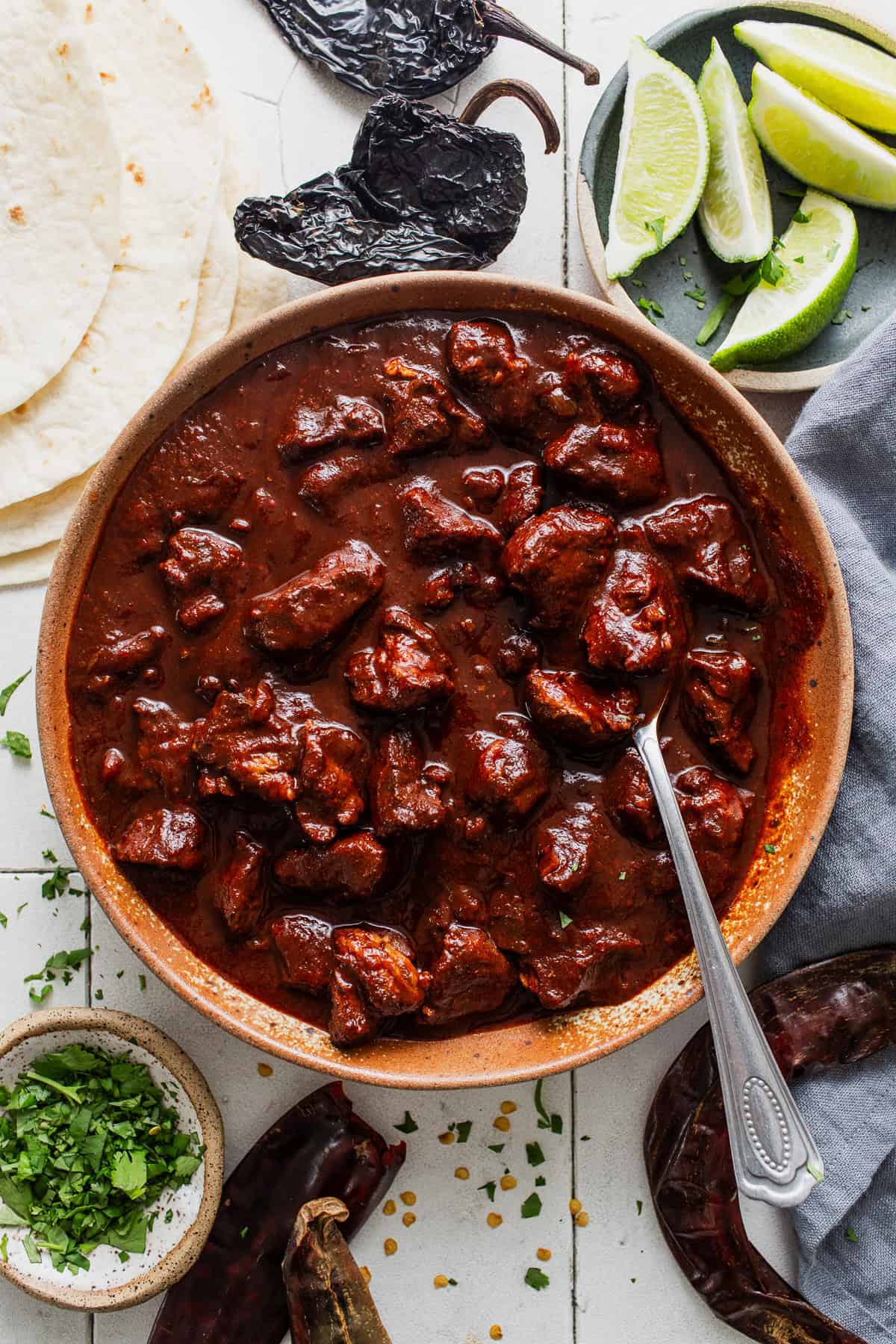 Carne adovada in a bowl next to warm tortillas.