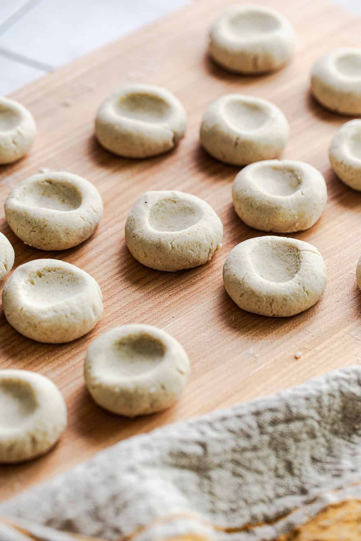 Formed chochoyotes on a cutting board, each with a small indentation pressed in the center.