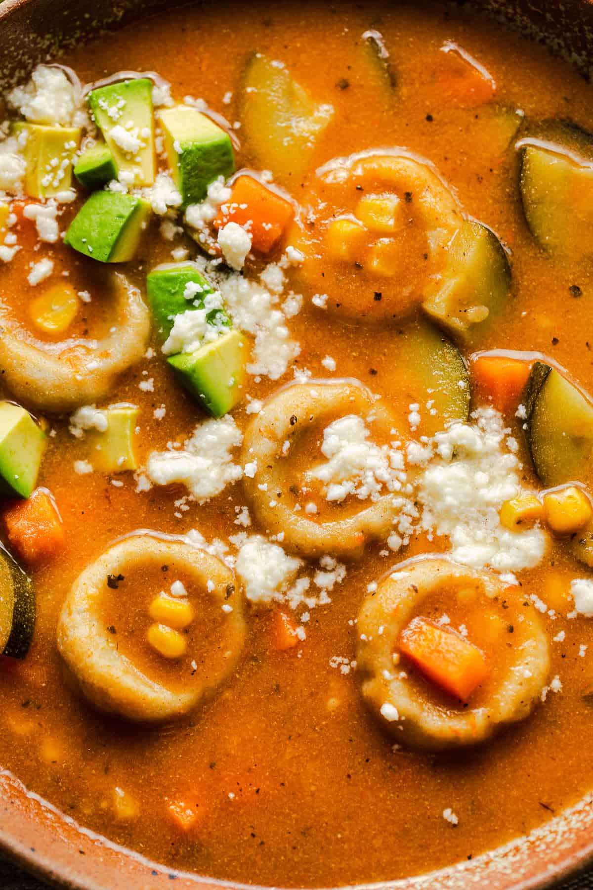 Chocoyotes in a brothy vegetable soup topped with crumbled queso fresco and some diced avocado.