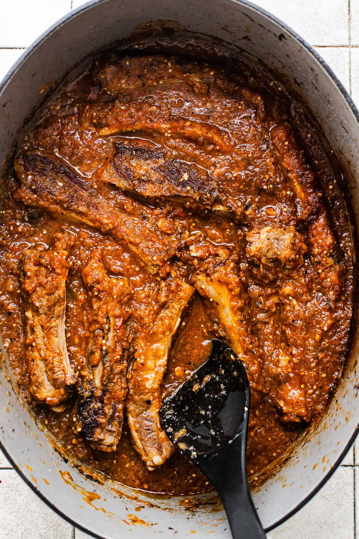 The pork ribs cooked in a salsa in a large Dutch oven.