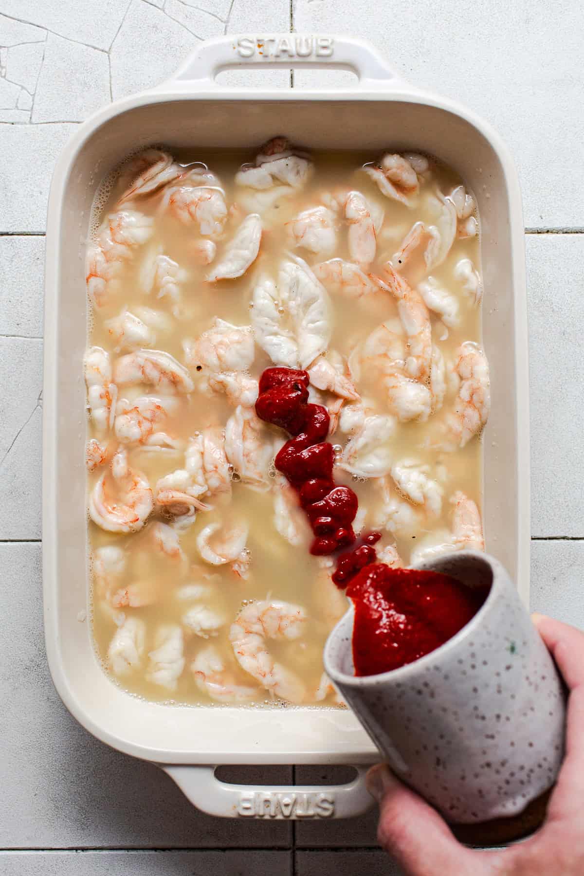 Shrimp that has been cured in lime juice that's pink and "cooked" with a red chile sauce being poured into it for aguachile rojo.