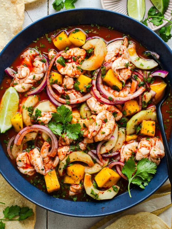 Aguachile rojo in a bowl with cucumber, mango, and red onion served with tostadas.