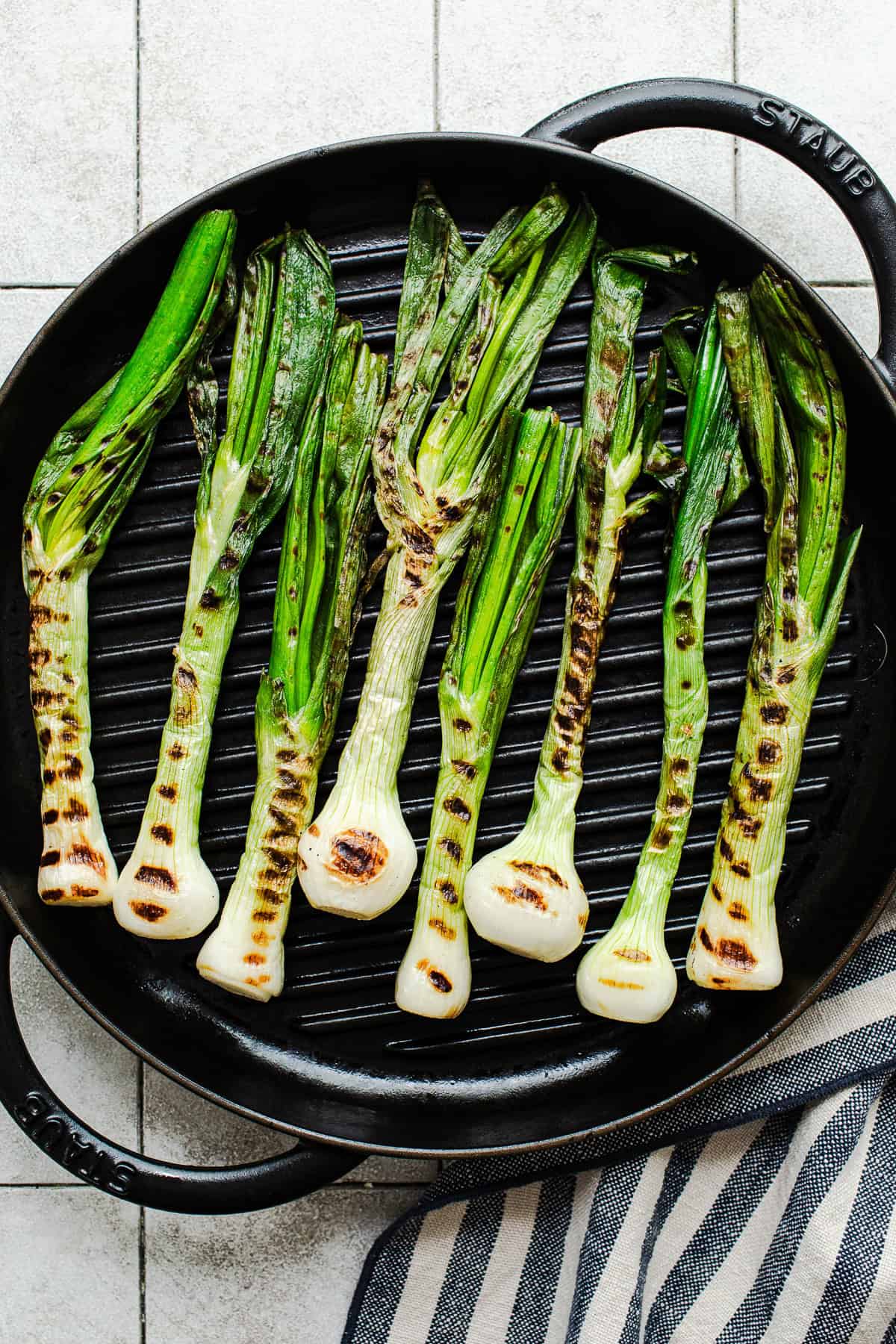 Cebollitas asadas charring on a grill pan until soft and blistered.