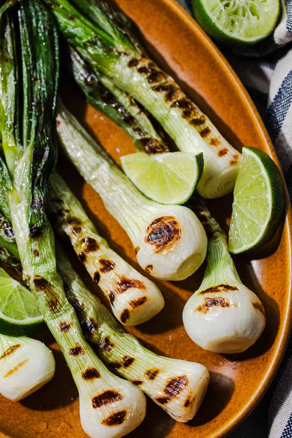 Close up of grilled cebollitas cambray with lime wedges ready to eat.